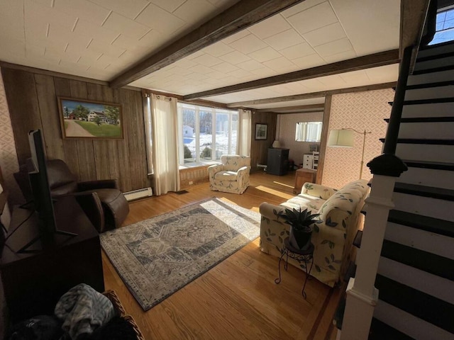 38 Atkinson Rd, Charleston, ME 04422 - living room with baseboard heating, wood finished floors, wooden walls, beam ceiling, and stairway