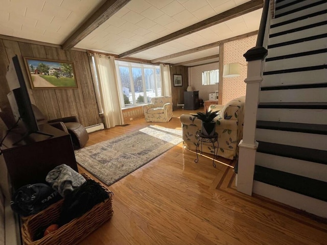 38 Atkinson Rd, Charleston, ME 04422 - living area featuring beamed ceiling, wood finished floors, wooden walls, baseboard heating, and stairs