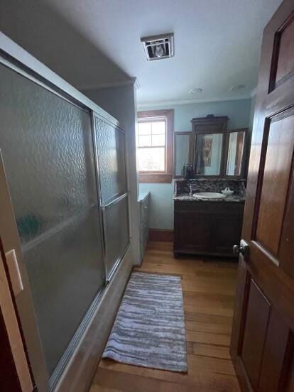 38 Atkinson Rd, Charleston, ME 04422 - full bathroom featuring wood finished floors, vanity, ornamental molding, and combined bath / shower with glass door
