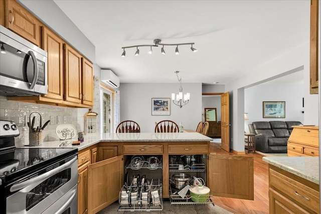 21 Bowling Green Ln, Belfast, ME 04915 - kitchen featuring appliances with stainless steel finishes, a peninsula, a chandelier, light countertops, and decorative backsplash
