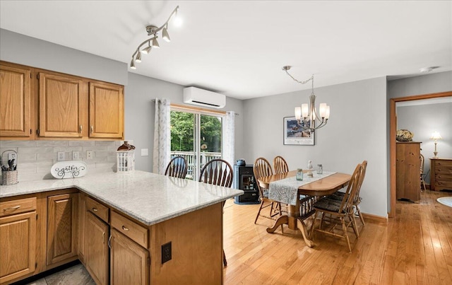 21 Bowling Green Ln, Belfast, ME 04915 - kitchen with an AC wall unit, tasteful backsplash, a chandelier, light wood-style flooring, and a peninsula