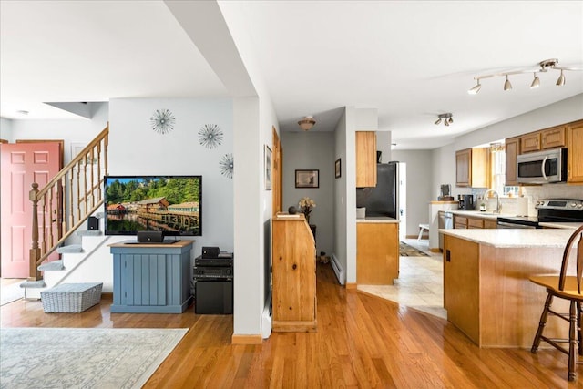 21 Bowling Green Ln, Belfast, ME 04915 - kitchen featuring appliances with stainless steel finishes, light countertops, light wood-type flooring, a breakfast bar area, and brown cabinets