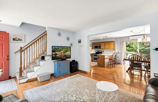 21 Bowling Green Ln, Belfast, ME 04915 - living room with a chandelier, light wood finished floors, stairway, and an AC wall unit