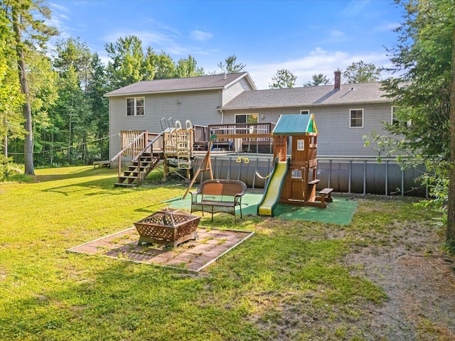 2 Bryer Heights Rd, Milford, ME 04461 - back of property with a fire pit, a deck, a playground, a chimney, and stairway