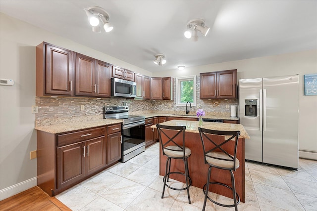 2 Bryer Heights Rd, Milford, ME 04461 - kitchen featuring appliances with stainless steel finishes, decorative backsplash, light stone counters, a kitchen island, and a kitchen bar