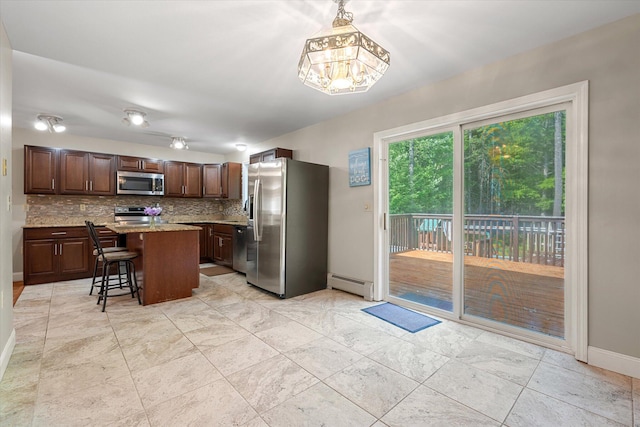2 Bryer Heights Rd, Milford, ME 04461 - kitchen featuring stainless steel appliances, a baseboard radiator, tasteful backsplash, a kitchen island, and a breakfast bar area