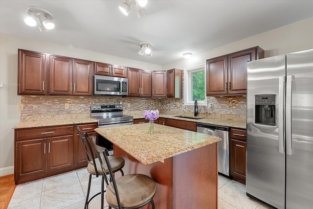 2 Bryer Heights Rd, Milford, ME 04461 - kitchen with appliances with stainless steel finishes, a breakfast bar area, decorative backsplash, a kitchen island, and light stone counters
