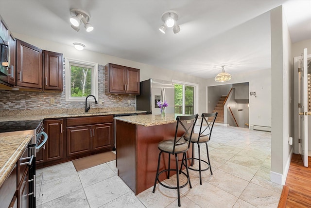 2 Bryer Heights Rd, Milford, ME 04461 - kitchen featuring stainless steel appliances, a breakfast bar, backsplash, a baseboard heating unit, and a center island