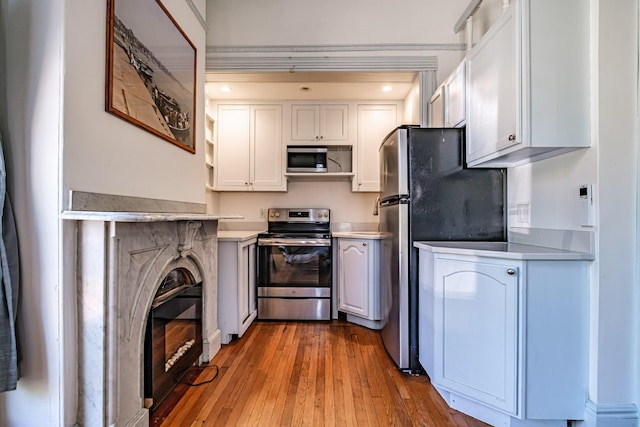 12 Deering St Unit 1, Portland, ME 04101 - kitchen with appliances with stainless steel finishes, light countertops, hardwood / wood-style flooring, and white cabinetry