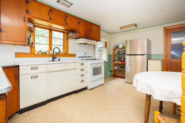 103 Mountain View Rd, Farmington, ME 04938 - kitchen with white gas range, freestanding refrigerator, light countertops, light floors, and brown cabinetry