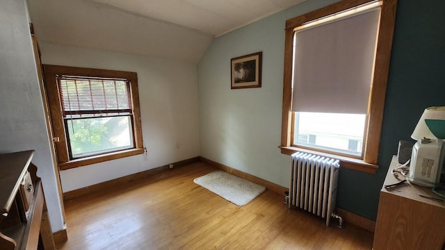 28 Eastland Ave, Millinocket, ME 04462 - empty room featuring radiator, lofted ceiling, wood finished floors, and plenty of natural light