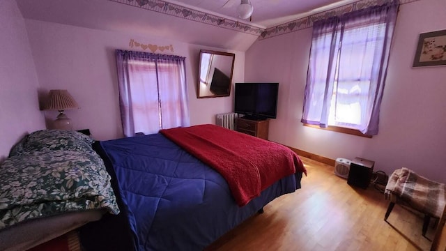 28 Eastland Ave, Millinocket, ME 04462 - bedroom featuring radiator heating unit, multiple windows, wood finished floors, and vaulted ceiling