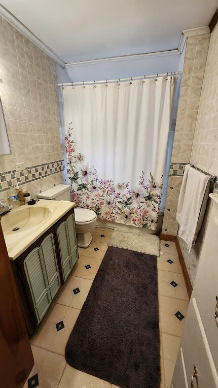 28 Eastland Ave, Millinocket, ME 04462 - full bath with tile patterned flooring, tile walls, vanity, crown molding, and shower / bath combination with curtain