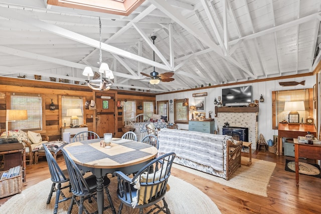 94 Crest Ave, Boothbay Harbor, ME 04538 - dining room featuring wood walls, a fireplace, light wood-type flooring, high vaulted ceiling, and a chandelier