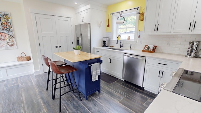 42 Hillside Rd, Orono, ME 04473 - kitchen with stainless steel appliances, a kitchen bar, white cabinets, backsplash, and dark wood finished floors