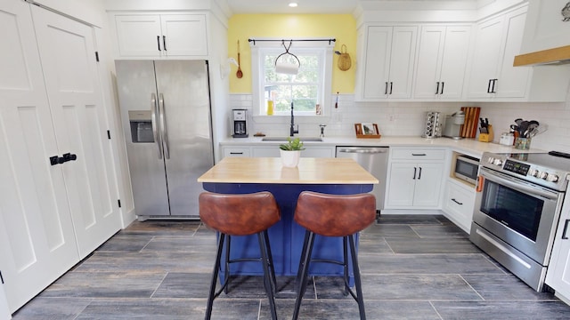 42 Hillside Rd, Orono, ME 04473 - kitchen featuring appliances with stainless steel finishes, custom exhaust hood, white cabinetry, a center island, and tasteful backsplash