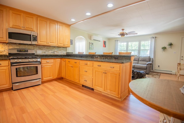 133 Ohio St, Millinocket, ME 04462 - kitchen featuring appliances with stainless steel finishes, arched walkways, a wall mounted air conditioner, light wood finished floors, and recessed lighting