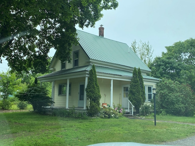 65 Quarry Rd, Sullivan, ME 04664 - view of front of home with a chimney, covered porch, a front lawn, and a metal roof