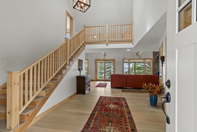 86 City Point Rd, Vinalhaven, ME 04863 - foyer entrance with stairway, a high ceiling, wood finished floors, and a chandelier