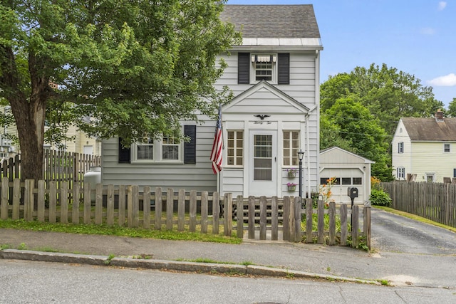 22 Cobb Rd, Bath, ME 04530 - view of front of home featuring a garage, roof with shingles, a fenced front yard, asphalt driveway, and an outbuilding