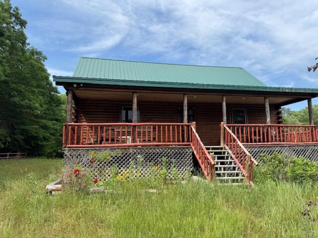 302 Haines Corner Rd, Livermore Falls, ME 04254 - view of front of house featuring log siding, covered porch, and a metal roof