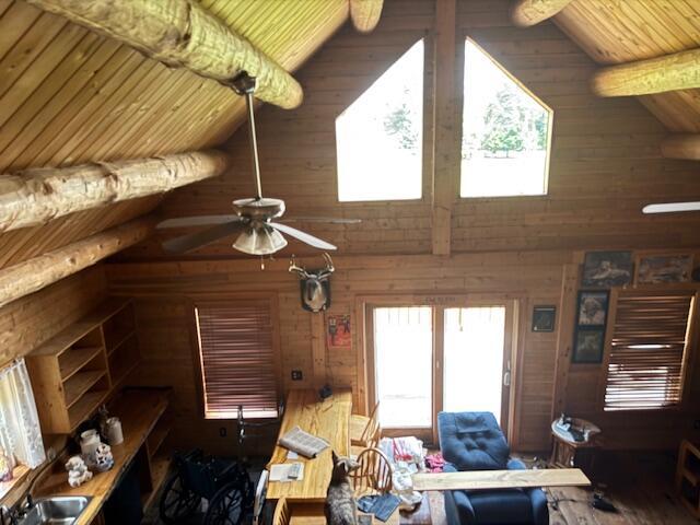 302 Haines Corner Rd, Livermore Falls, ME 04254 - living area with high vaulted ceiling, healthy amount of natural light, ceiling fan, a wooden ceiling with exposed beams, and wooden walls