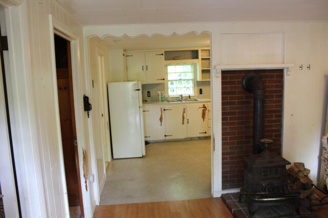7 Maple St, Milbridge, ME 04658 - kitchen with freestanding refrigerator, a wood stove, light countertops, and light wood-type flooring