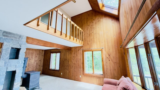 270 Grant Rd, Sullivan, ME 04664 - carpeted living room featuring wooden walls, a wood stove, and high vaulted ceiling