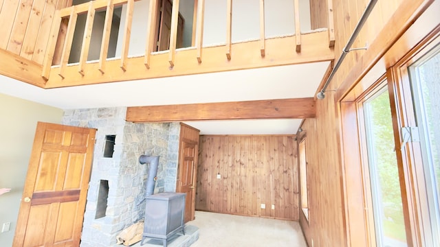 270 Grant Rd, Sullivan, ME 04664 - unfurnished living room with a wood stove, beamed ceiling, wood walls, and carpet