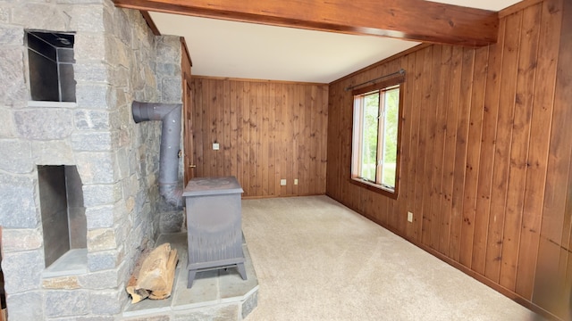 270 Grant Rd, Sullivan, ME 04664 - unfurnished living room with beam ceiling, wood walls, carpet floors, and a wood stove