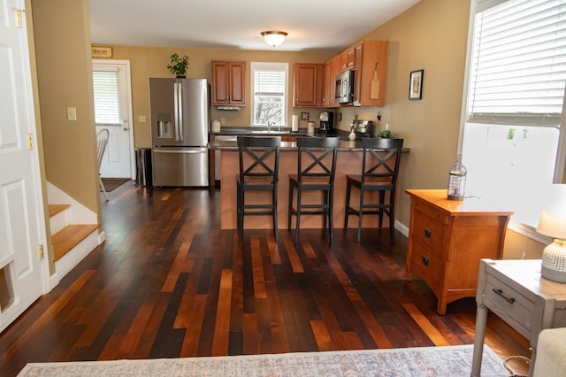 13 Bremen St, Westbrook, ME 04092 - kitchen with stainless steel appliances, healthy amount of natural light, brown cabinets, and a peninsula