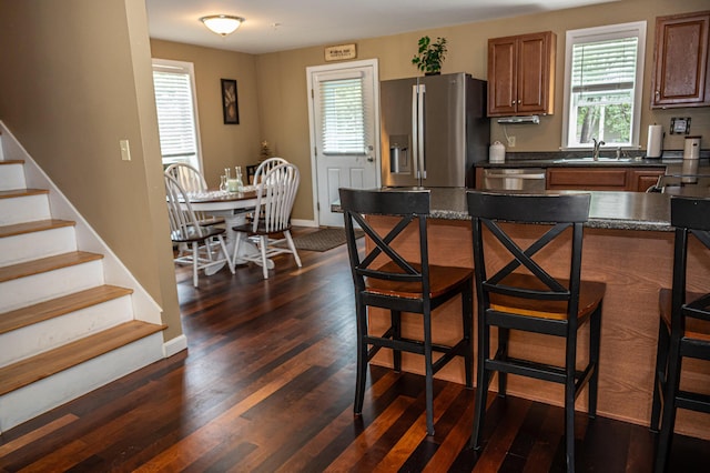 13 Bremen St, Westbrook, ME 04092 - kitchen featuring appliances with stainless steel finishes, dark countertops, a breakfast bar area, brown cabinets, and dark wood-type flooring