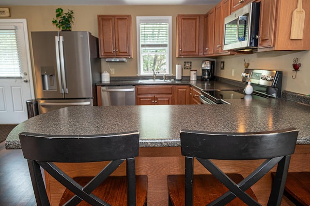 13 Bremen St, Westbrook, ME 04092 - kitchen featuring stainless steel appliances, dark countertops, a peninsula, and brown cabinets