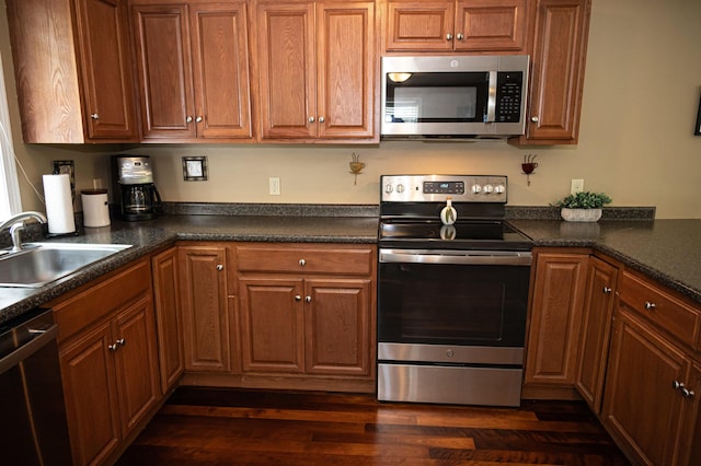13 Bremen St, Westbrook, ME 04092 - kitchen featuring stainless steel appliances, dark countertops, dark wood-style flooring, and brown cabinetry