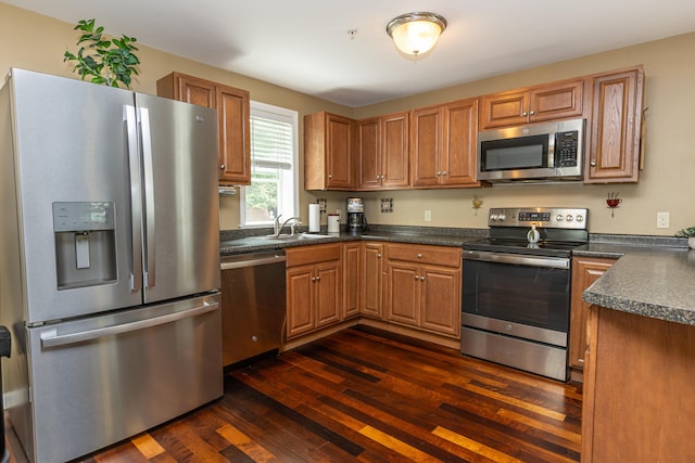 13 Bremen St, Westbrook, ME 04092 - kitchen featuring appliances with stainless steel finishes, dark countertops, dark wood-style floors, and brown cabinets