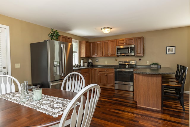 13 Bremen St, Westbrook, ME 04092 - kitchen featuring stainless steel appliances, dark countertops, a peninsula, dark wood-type flooring, and a kitchen breakfast bar