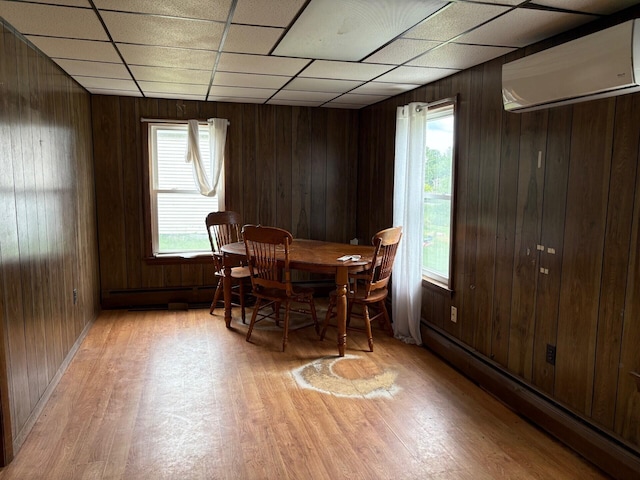 41 S Main St, Burnham, ME 04922 - dining room with baseboard heating, a wall unit AC, light wood-type flooring, wood walls, and a drop ceiling