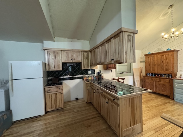 1698 Exeter Rd, Exeter, ME 04435 - kitchen with freestanding refrigerator, tile counters, vaulted ceiling, light wood finished floors, and tasteful backsplash