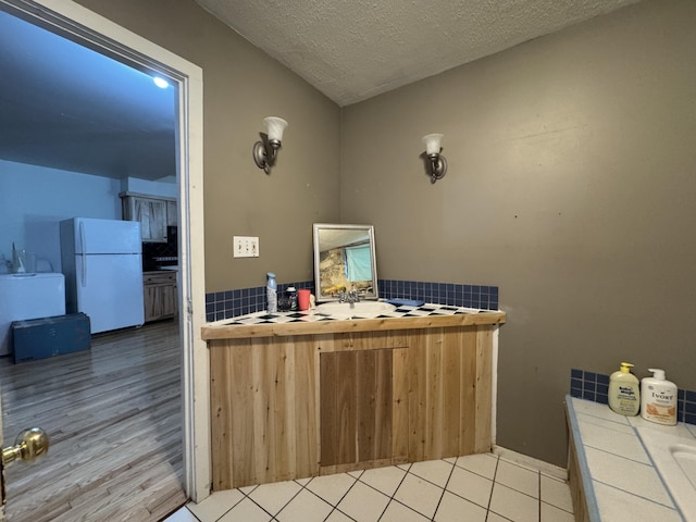 1698 Exeter Rd, Exeter, ME 04435 - kitchen with tile countertops, freestanding refrigerator, a textured ceiling, wood finished floors, and backsplash