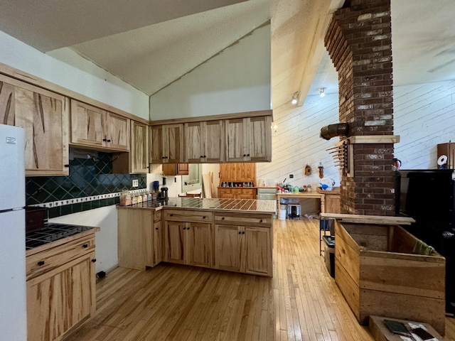 1698 Exeter Rd, Exeter, ME 04435 - kitchen with freestanding refrigerator, light wood-type flooring, decorative backsplash, tile countertops, and high vaulted ceiling