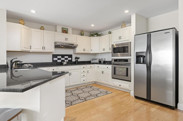 1 E Grand Ave Unit 503, Old Orchard Beach, ME 04064 - kitchen featuring stainless steel appliances, under cabinet range hood, light wood finished floors, dark stone countertops, and a peninsula