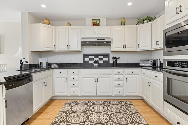 1 E Grand Ave Unit 503, Old Orchard Beach, ME 04064 - kitchen with stainless steel appliances, under cabinet range hood, light wood-type flooring, recessed lighting, and white cabinetry
