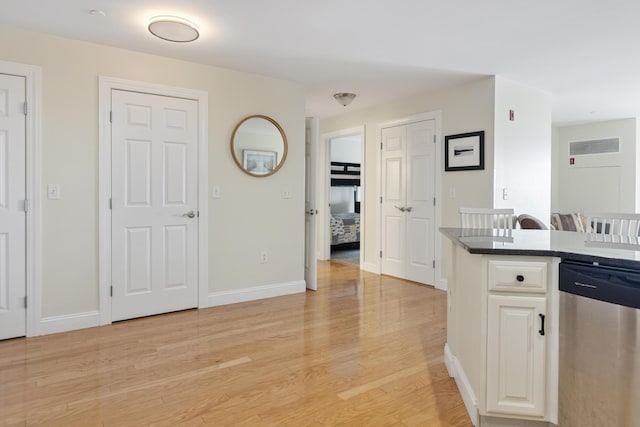 1 E Grand Ave Unit 503, Old Orchard Beach, ME 04064 - kitchen with stainless steel dishwasher, light wood-style floors, white cabinetry, and dark countertops