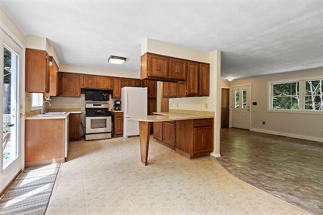 2672 N Belfast Ave, Augusta, ME 04330 - kitchen with stainless steel range with gas cooktop, black microwave, freestanding refrigerator, light countertops, and a peninsula