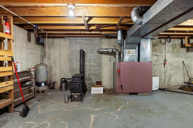 2672 N Belfast Ave, Augusta, ME 04330 - unfinished basement featuring a wood stove, heating unit, and a water pressure tank