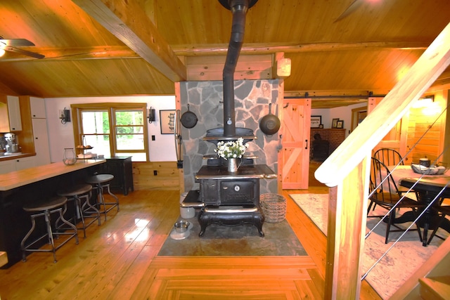 108 Maple Rd, Atkinson, ME 04426 - living area with a wood stove, wood ceiling, hardwood / wood-style flooring, a ceiling fan, and stairway