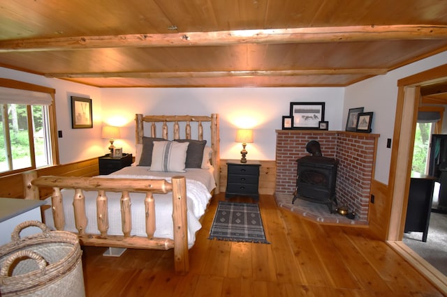 108 Maple Rd, Atkinson, ME 04426 - bedroom with a wood ceiling with exposed beams, a wood stove, and hardwood / wood-style flooring