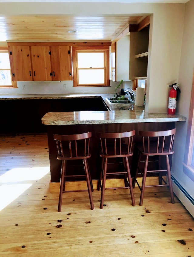 120 Sunday River Rd, Bethel, ME 04217 - kitchen featuring light wood-type flooring, light stone countertops, a kitchen bar, and a peninsula