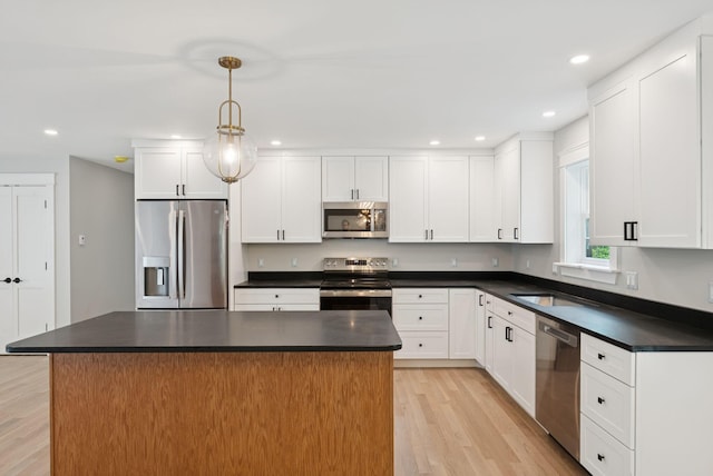 127 Bond Brook Rd, Augusta, ME 04330 - kitchen featuring stainless steel appliances, dark countertops, light wood-type flooring, white cabinetry, and hanging light fixtures