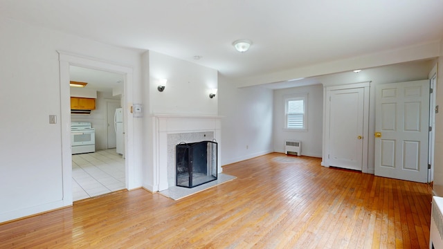69 Androscoggin Ave, Lewiston, ME 04240 - unfurnished living room with radiator heating unit, light wood finished floors, and a fireplace